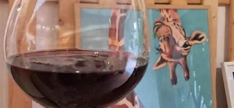 Illustrated giraffe holding a glass of wine, the signature artwork of Hidden Giraffe Gallery Café.