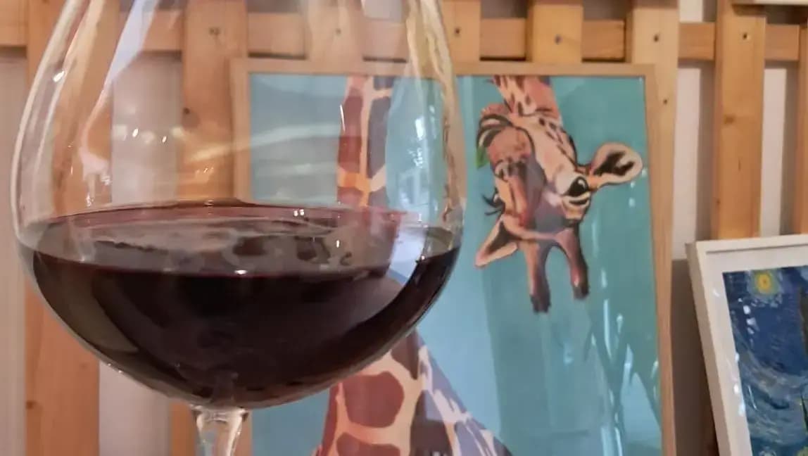 Red wine and original giraffe artwork at Hidden Giraffe gallery café in Prague